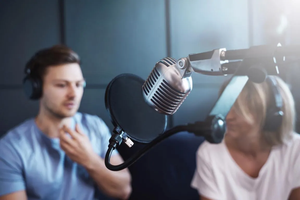 Aufnahme Podcast Eine Mann und eine Frau tragen Kopfhöhrer und sprechen in ein Mikrofon